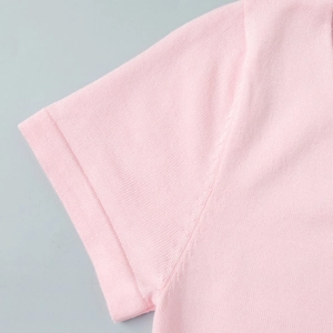 Close-up of pink knit dress sleeve showing fine horizontal texture and neat cuff stitching