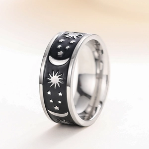 Macro shot of silver metal ring featuring black enamel moon and star celestial patterns