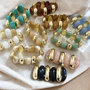 Detailed view of colorful acrylic resin and polished metal block stretch bracelets on burlap