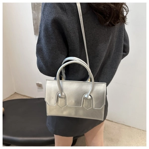 Silver PU leather crossbody bag worn as a shoulder bag by model in a minimalist setting