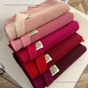 Detail shot of soft cashmere-feel scarves showing fine texture in various red and pink shades