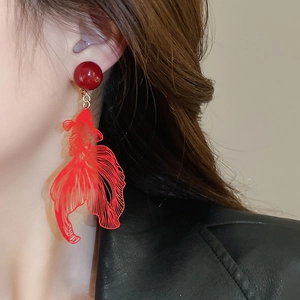 Macro shot of red goldfish earrings featuring translucent tail details and gold metal finish