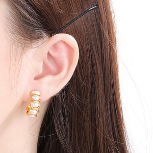 Close-up of elegant gold C-shaped earrings with white pearls on model ear