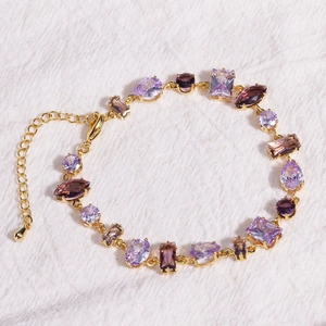 Detailed view of golden bracelet with purple stones on textured white fabric