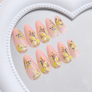 Almond shaped press on nails with yellow floral patterns on translucent pink base