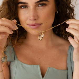 Golden link chain necklace with butterfly, purple gemstone, and oval medal pendants on model