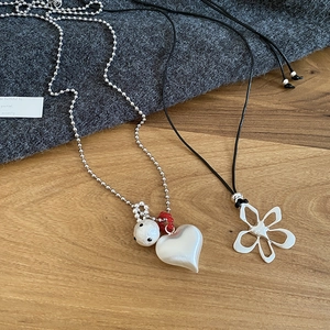 Minimalist heart pendant and hollow flower necklace on elegant wooden and fabric background