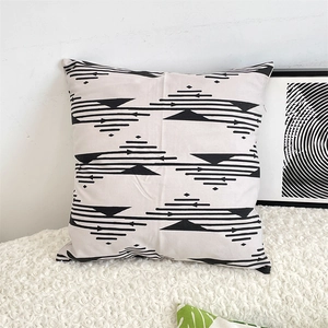 Modern black geometric pattern on a beige cotton linen cushion cover on a white sofa