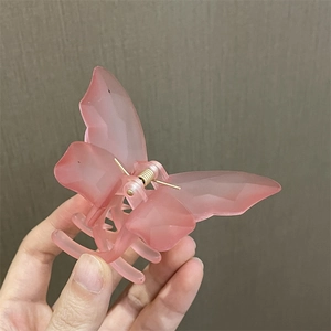 Vista detallada de una pinza para el pelo de mariposa en resina rosa mate suave