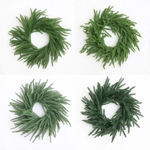 Artificial Norfolk pine Christmas wreath in four green shades on white wooden background