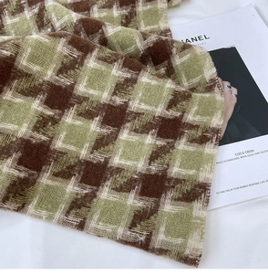 Close-up of thick houndstooth scarf texture in brown and green with soft wool-like finish