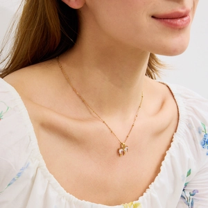 Détail d'un collier pendentif nœud doré avec zircons et chaîne à billes sur mannequin