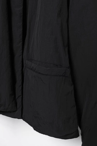 Detailansicht einer schwarzen Steppjacke mit Klappentasche und glatter Nylon-Stoffstruktur