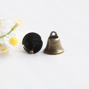 Detailed view of vintage bronze metal bells for DIY crafts with a white floral background