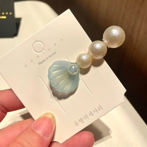 Detail of light blue shell hair clip with pearls on a golden metal duckbill base