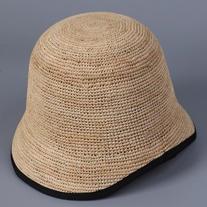 Detailed texture of raffia straw bucket hat with black ribbon edge and tight weaving