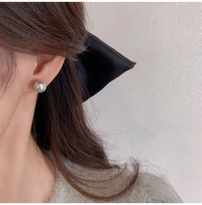 Close-up of elegant grey pearl stud earrings on a model showing shimmering luster