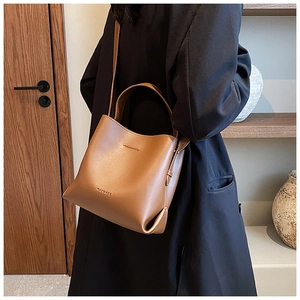 Brown leather bucket bag styled on shoulder showing size and texture in lifestyle setting
