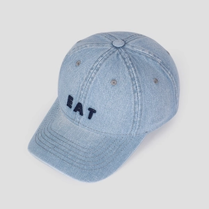 Detail of the blue denim baseball cap featuring high-quality EAT embroidery on the front