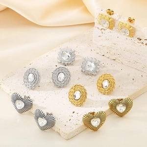 Detailed view of square and heart-shaped gold studs with clear crystals and textures