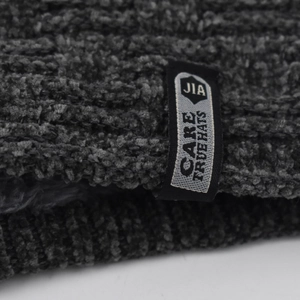 Macro shot of dark gray chenille knit texture and sewn label on the winter beanie