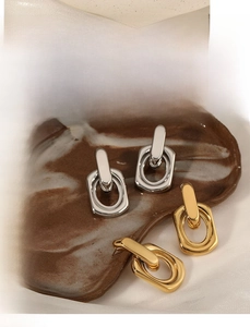 Detail of geometric interlocking hoop earrings in polished gold and silver finish