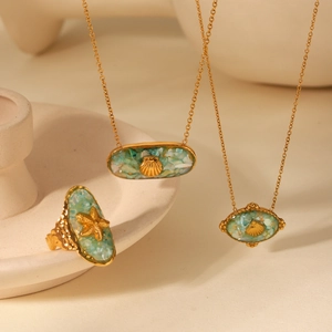 Close-up of gold shell and starfish necklaces with blue and green crushed stone inlay