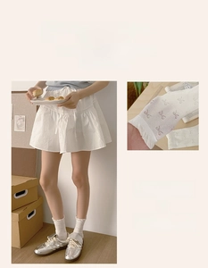 Close-up of white crew socks with pink bow patterns and ruffled cuffs for women