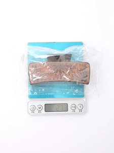 Detail view of sunflower embossed leather hair claw clip showing 27.3g weight on scale