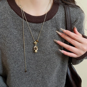 Détail d'un collier en Y doré avec charms étoile et perle porté par un mannequin femme