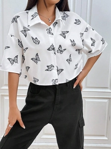Detalle de camisa blanca de manga corta con estampado de mariposas sobre fondo de madera