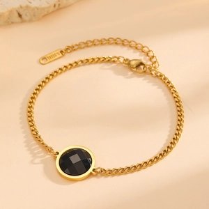 Detail of 18K gold plated stainless steel bracelet with a black faceted stone pendant