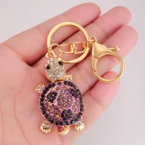 Close-up of golden turtle keychain featuring vibrant purple and black rhinestone shell detail