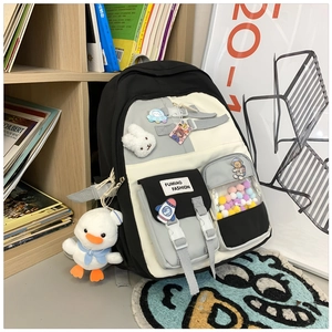Detail of school backpack with cute plush bunny charm and astronaut badges on front pocket