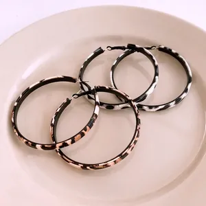 Fashionable large hoop earrings with leopard and zebra patterns on a ceramic tray