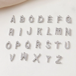 Macro shot of 26 sparkling silver letter pendants with clear cubic zirconia inlays