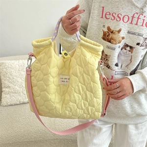 Détail du sac fourre-tout matelassé jaune avec bandoulière rose et poignée violette
