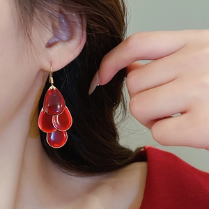 Detail of red layered water drop earrings with gold hooks worn by a model