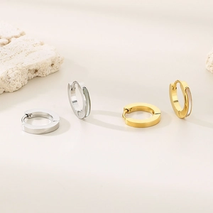 Detailed view of geometric hoop earrings in gold and silver with white shell inlay