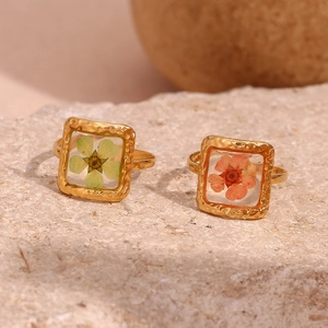 Detailed shot of gold hammered rings with dried green and orange flowers on stone