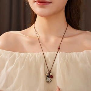 Detail of bohemian heart necklace featuring spotted stone pendant with a silver cross