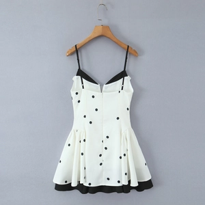 Vue de face robe courte blanche à pois avec fines bretelles noires sur cintre en bois