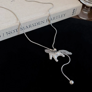 Macro shot of silver hollow horse pendant with tassel on black velvet and book background