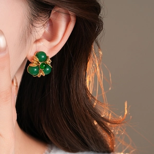 Gros plan détaillé d'une boucle d'oreille vintage fleur dorée et perle verte sur modèle