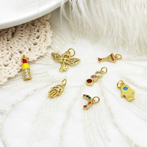 Assorted 18K gold plated charms with colorful crystals on white lace background