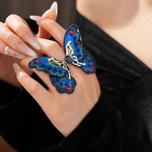 Detailed view of an embroidered butterfly ring with crystals and metal frame