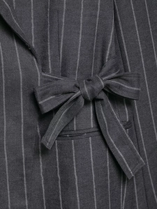 Macro shot of striped blazer fabric detail with a decorative 3D bow tie embellishment