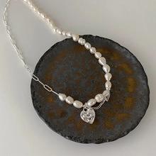Detailed macro of baroque freshwater pearls and silver heart pendant on chain necklace