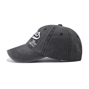 Detail of NY white embroidery on dark gray washed cotton baseball cap with side stitching