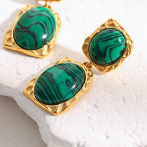 Détail de boucles d'oreilles plaquées or 18 carats avec malachite sur pierre blanche
